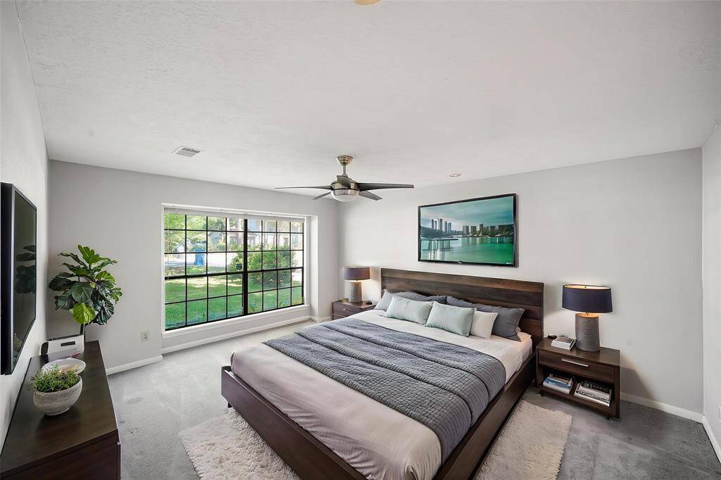 Virtually Staged: Incredible primary bedroom with carpet floors, a ceiling fan, and large windows.