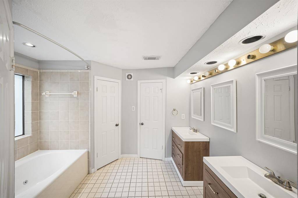 This primary bathroom has tile floors, and multiple walk-in closets.