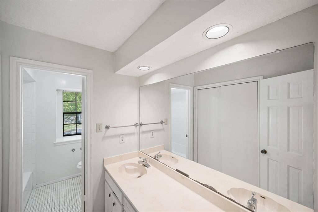 Secondary bathroom with tile floors, double sinks, and a large mirror.
