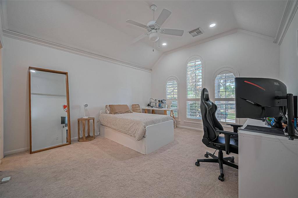 The third bedroom includes charming arched windows with plantation shutters, a vaulted ceiling with recessed lighting, and a spacious layout perfect for rest or study.