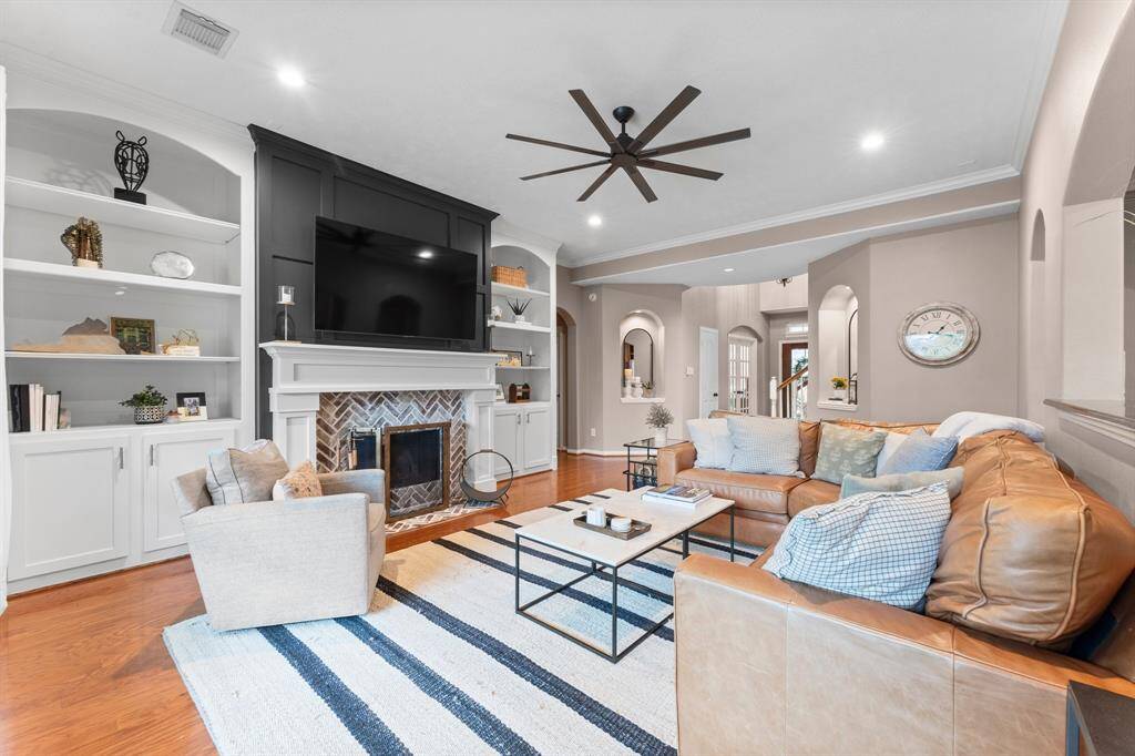 The heart of this inviting Family Room is the stately remodeled brick fireplace(2021) with a convenient gas starter, offering both warmth and style. It is flanked by newly-added custom bookshelves—perfect for additional electronics or shelving for your favorite collectibles. Designed for both function and comfort, this room also features wood flooring, recessed lighting, ceiling fan, crown molding, and two lighted art niches. Click on the movie reel icon to see our walk-through video of this space!