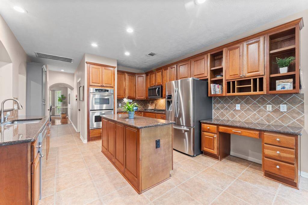 Gourmet chefs and home cooks alike will love this spacious kitchen, featuring arched entryways, recessed lighting, tile flooring, a large island for additional storage,  sleek granite countertops, and stainless steel appliances including a 5 burner cooktop, double ovens (one convection), dishwasher, microwave, and refrigerator/freezer. Plenty of room to create, gather, and enjoy!