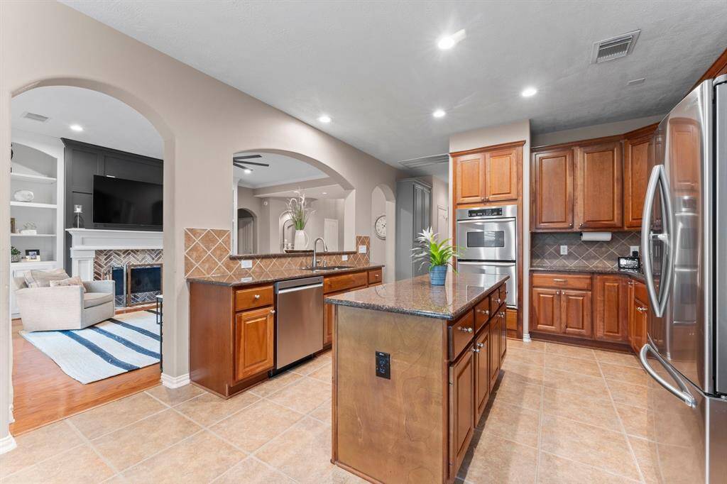 The kitchen is a stunning blend of modern elegance and function. A diamond-laid tile backsplash creates a refined aesthetic, while a spacious walk-in pantry with shelving and additional under-stair space offers exceptional storage. There is also a convenient  floor-to-ceiling cabinet next to the pantry. The large sink with a pull-out sprayer makes clean-up a breeze. A true chef’s kitchen designed for everyday living and grand gatherings alike.