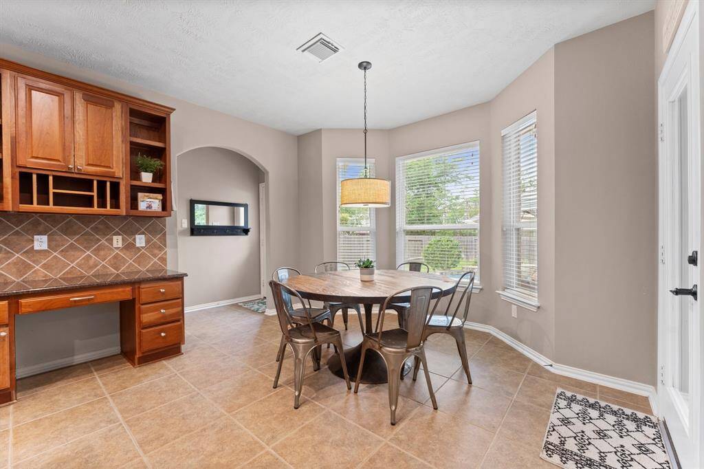 Start your mornings with a cup of coffee or gather for family dinners in this inviting breakfast area! Featuring tile flooring, a sunny bay window, and a decorative light fixture, this space is filled with natural light. There is also a convenient desk with shelving and drawers to keep everything organized.
