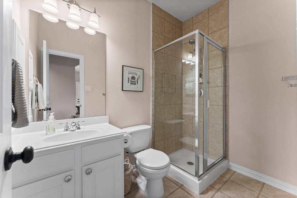 This conveniently-located first-floor bathroom is perfect for pool guests, allowing them to freshen up without tracking water through the home. It features tile flooring, a single sink, medicine cabinet, and a tiled shower.