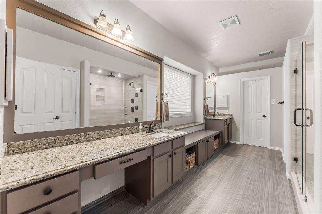 Truly a retreat for getting ready on a busy morning or stealing away for an evening out, your en-suite bath was remodeled in 2017 and features tile flooring, dual vanities, framed mirrors, large shower, window with rain glass for privacy, linen closet, private commode, a dressing bench with storage, and large walk-in closet.