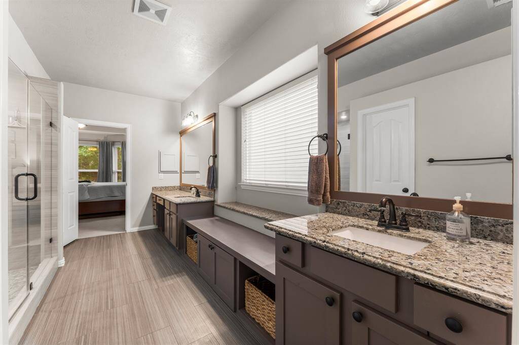 The dual vanities showcase rich cabinetry, gleaming granite counter tops, under-mount sinks, medicine cabinets, and large framed mirrors.  They each have their own corner in the room to allow plenty of space when getting ready. The built-in sit-down vanity space for her creates ample room for pampering, and the raised-height vanity for him is convenient for shaving.