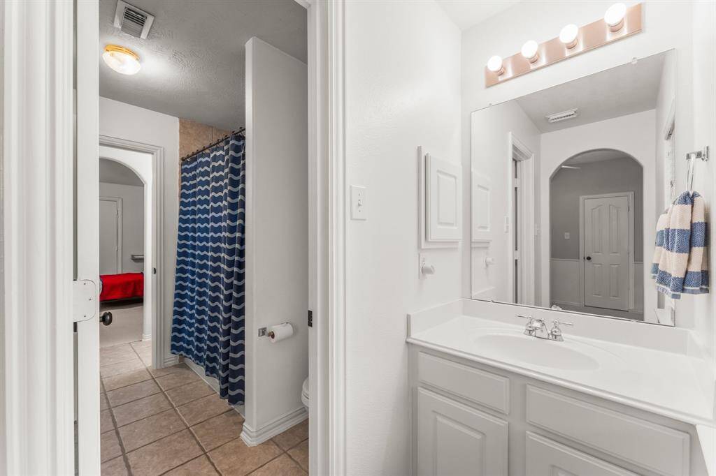 The Jack-and-Jill bathroom for Bedrooms 2 and 3  includes dual sinks, cultured marble countertops, tile flooring, linen closet, medicine cabinets, and a private area with toilet and tiled shower/tub combo with clerestory window.
