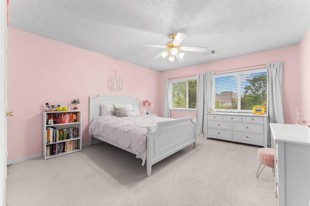 Another secondary bedroom offers lush carpeting, large walk-in closet, two sunny double windows with pool views, and lighted ceiling fan. It has hallway access to a full bath shared with Bedroom 4.