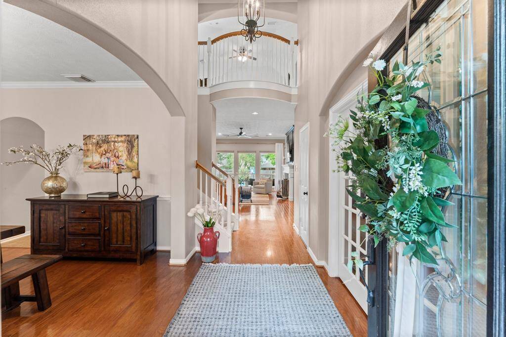 Step into sophisticated style with this stunning two-story foyer, where every detail is designed to impress. Elegant upgrades like double crown molding and the leaded glass and wood front door add to the refined craftsmanship throughout. The grand Foyer welcomes you with warm wood flooring, a stately iron chandelier, and convenient coat closet. From the moment you enter, you're greeted with breathtaking views extending through the living room to the expansive backyard and welcoming pool beyond."