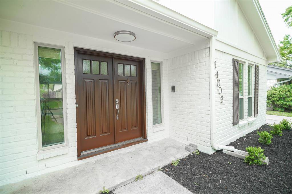 Welcome to 14003 Briarworth Dr. The exterior features whitewashed brick and siding, complemented by sleek landscaping and a hardwood entrance door.