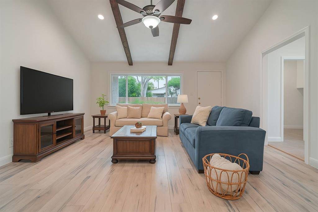 The open living area features a vaulted ceiling with exposed beams. Virtually enhanced.