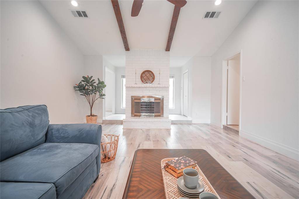 The open living area features a vaulted ceiling with exposed beams. The living area also features a gas log fire place.