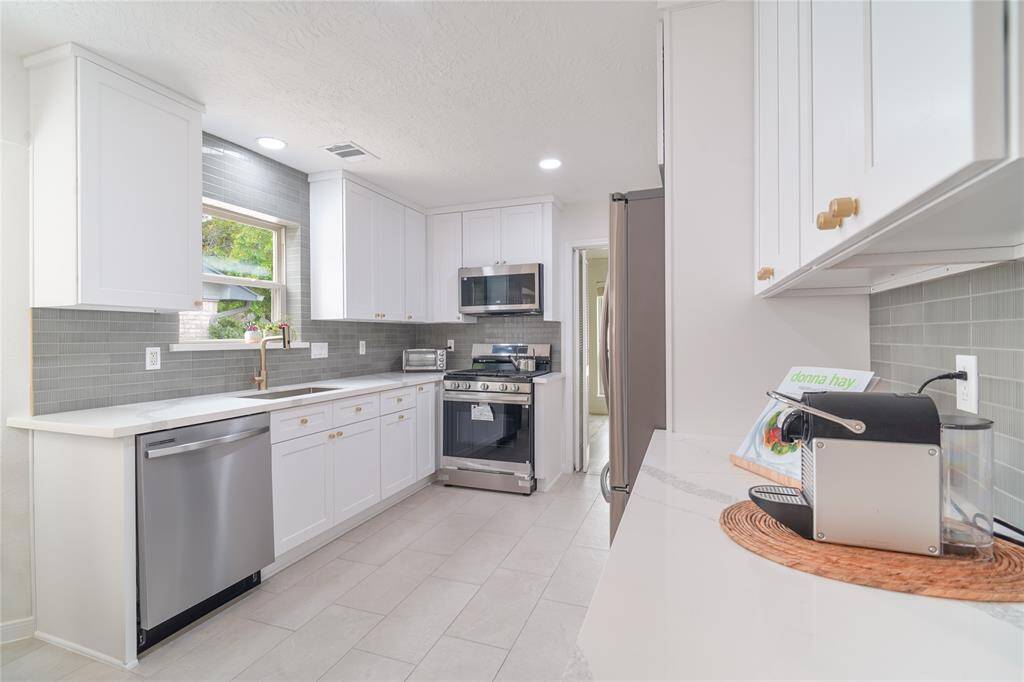 Renovated kitchen and breakfast nook. The Kitchen features soft-close hardwood cabinets all the way to the ceiling with quartz countertops and modern subway style backsplash. New tiles and new stainless steel appliances.