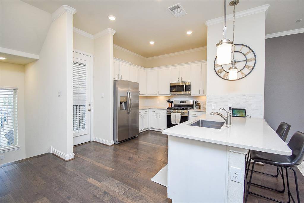 Kitchen features light & bright counters and backsplash, Shaker style cabinetry, and stainless appliances.