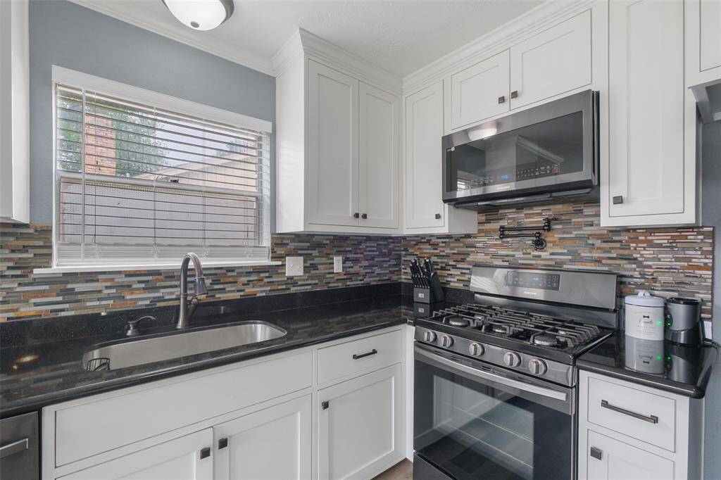 Stunning kitchen with gas range, sleek backsplash, and modern white cabinetry!