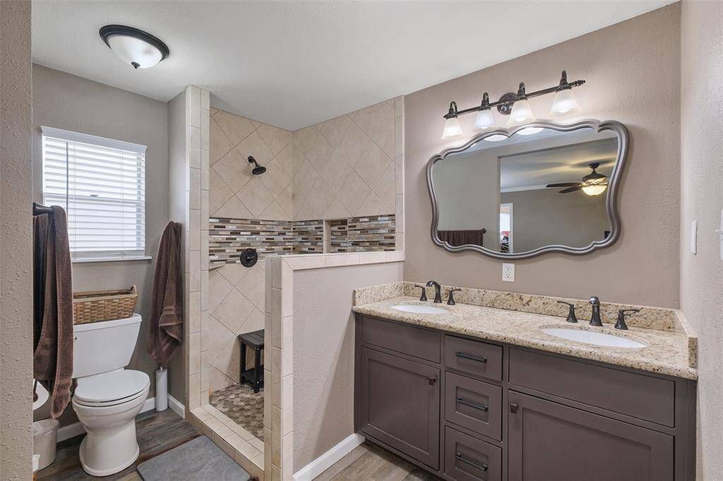 Elegant primary bath with dual sinks, granite counters, and a walk-in tile shower with seating!
