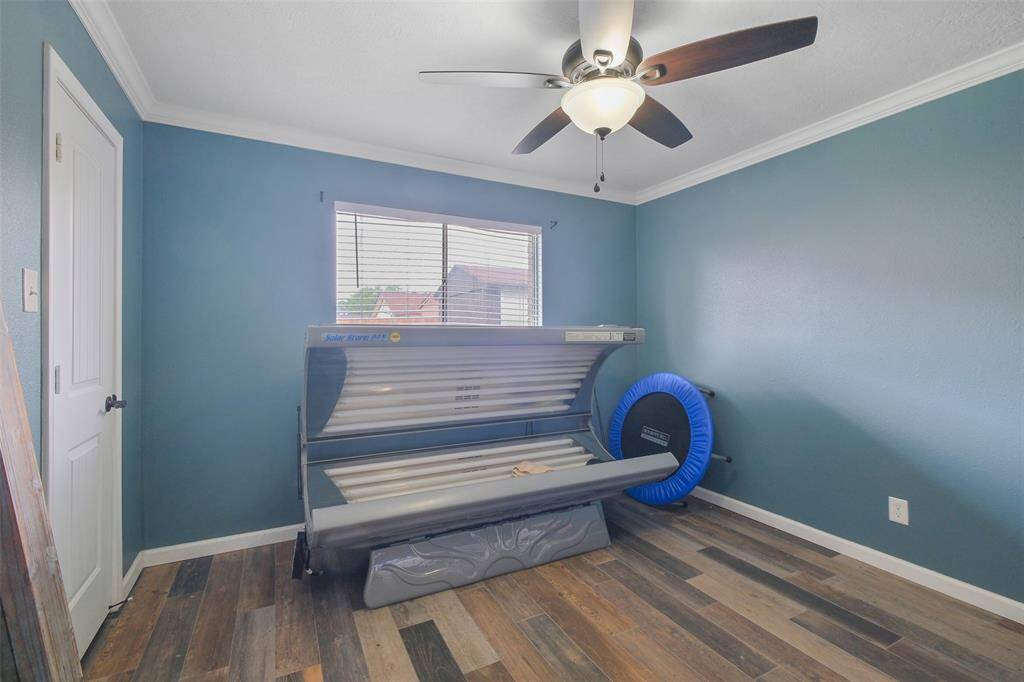 Versatile bedroom with crown molding, ceiling fan, and rich wood-look flooring throughout