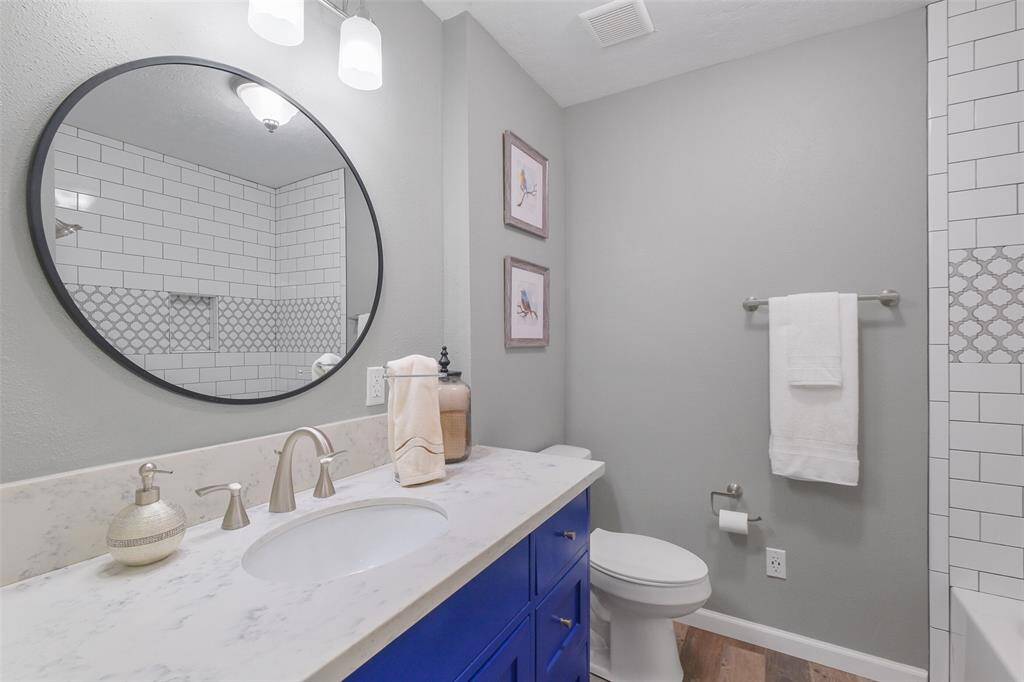 Stylish guest bath with bold vanity, marble top, and custom tile tub surround with niche detailing!