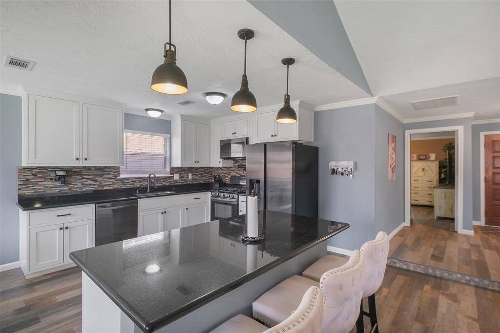 Modern kitchen with granite counters, pendant lighting, and sleek stainless steel appliances!