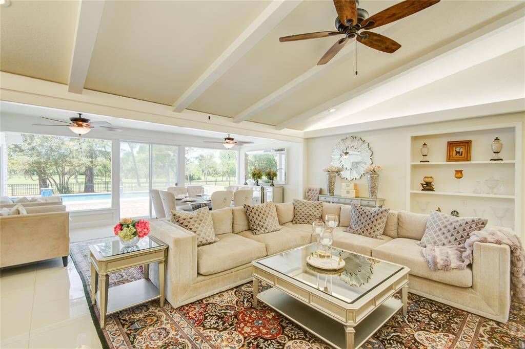 This alternate view of the family room showcases elegant built-in shelving, with the formal dining area just beyond, offering stunning pool and golf course views.