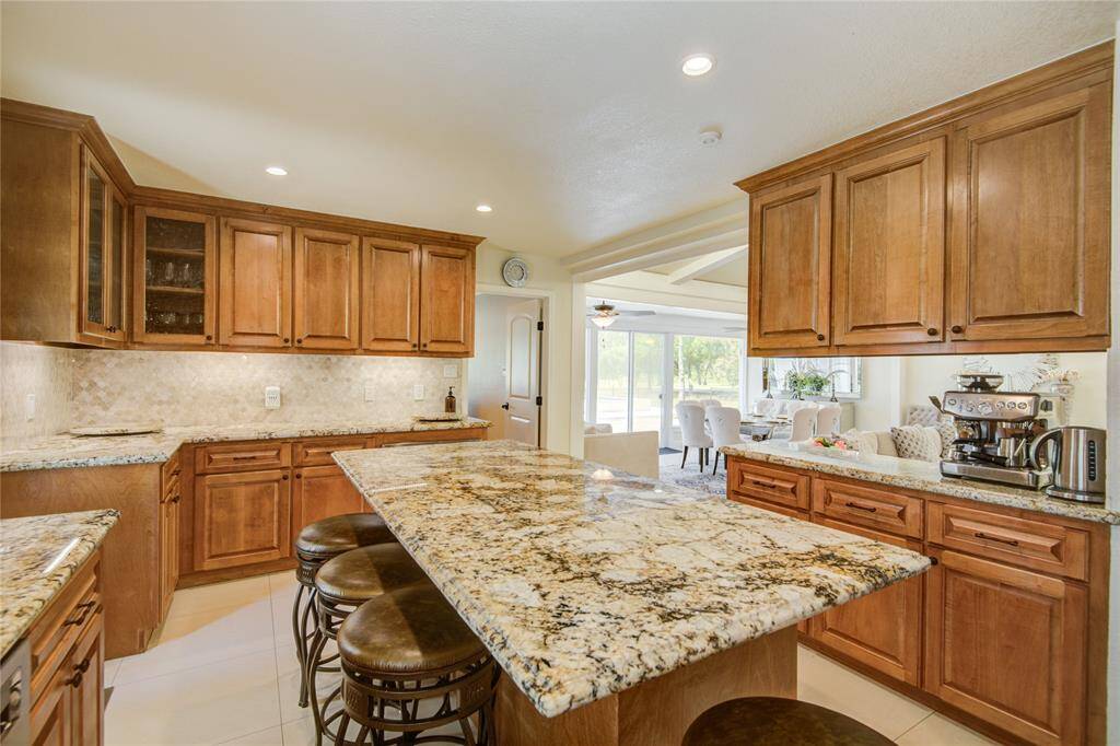 A view of the kitchen in the opposite direction reveals additional cabinets and counter space, while offering a seamless look into the open family and dining rooms, with a doorway ahead leading to the study.