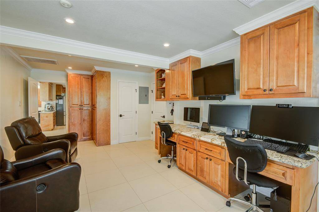 A spacious office, located just off the kitchen, features a convenient half bath, access to the workout room, and an abundance of natural light streaming through the windows.