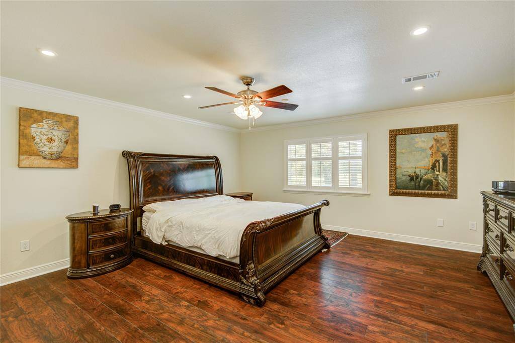 The primary bedroom features warm wood floors, multiple closets, a serene pool view, and a private en-suite bathroom for ultimate comfort and privacy.