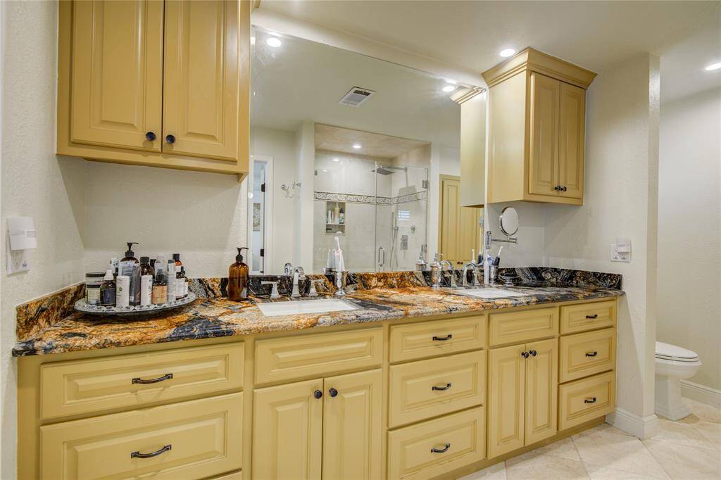The primary en-suite bathroom boasts stunning granite counters with dual sinks, added built-ins for extra storage, and an oversized shower with beautiful tile accents complete with inset niche for shampoos and soaps.