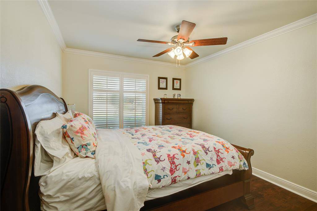 This first secondary bedroom continues the home's neutral palette, featuring crown molding and oversized windows that fill the room with natural light.