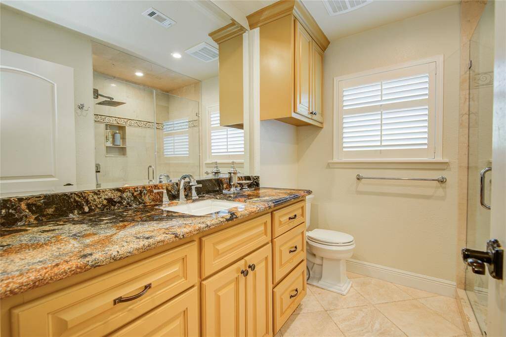 This spacious secondary bathroom features an oversized walk-in shower, along with plenty of counter and cabinet space for added convenience.