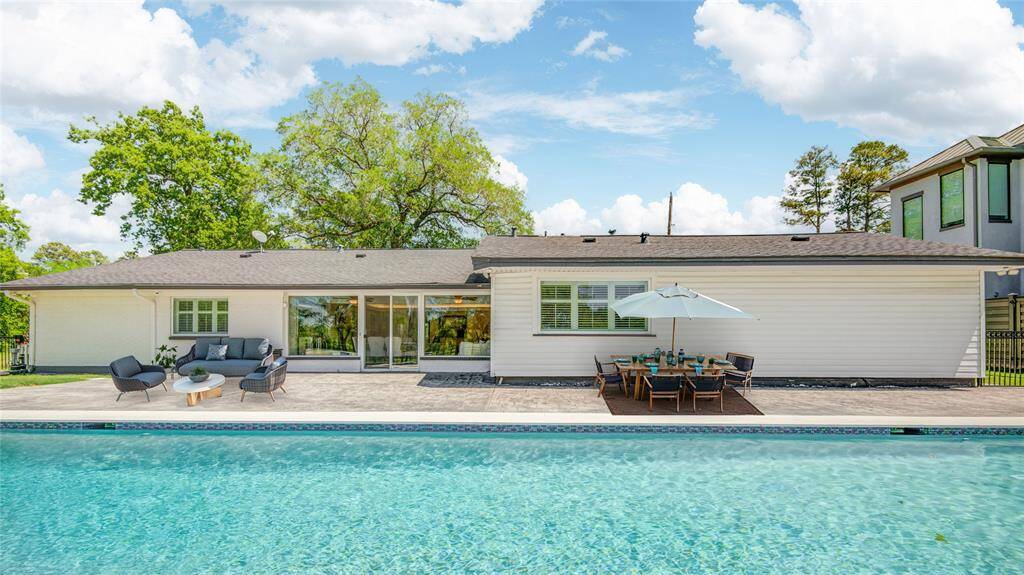 The back of the home showcases sleek, clean lines with a crystal-clear, inviting pool that enhances the home's appeal. (virtually staged)