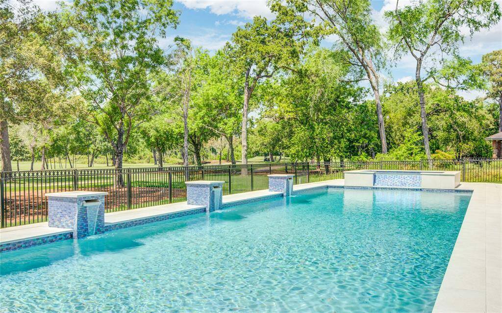 The pool, overlooking the golf course, features multiple waterfall elements along its backside, adding a tranquil touch to the outdoor space.