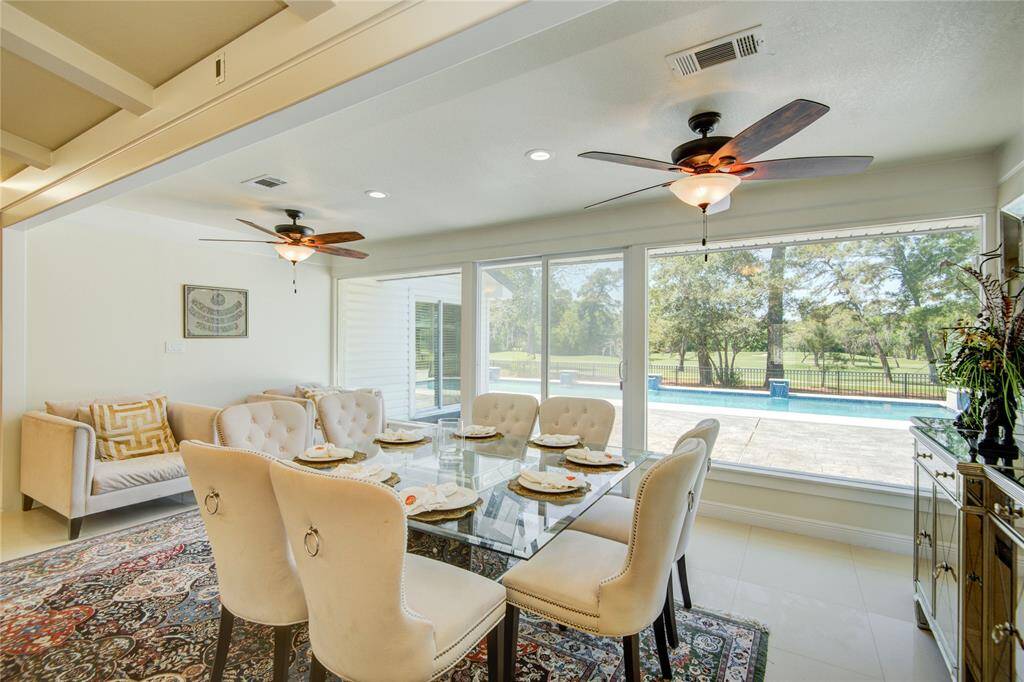 The expansive formal dining area offers ample space for additional seating on one side, a buffet on the other, and a large dining table, all framed by a wall of windows showcasing serene pool views beyond.