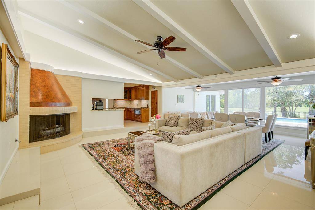 The bright family room features a cozy corner fireplace, vaulted ceiling with ambient surround and recessed lighting, and is open to the dining room and kitchen.