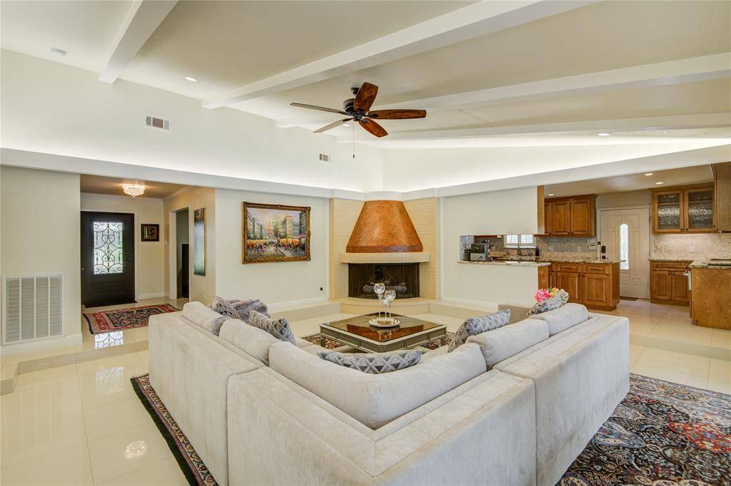 This family room view looks back towards the foyer, featuring a doorway to the left leading to the bedroom hallway, with a stunning curved fireplace positioned in the corner.