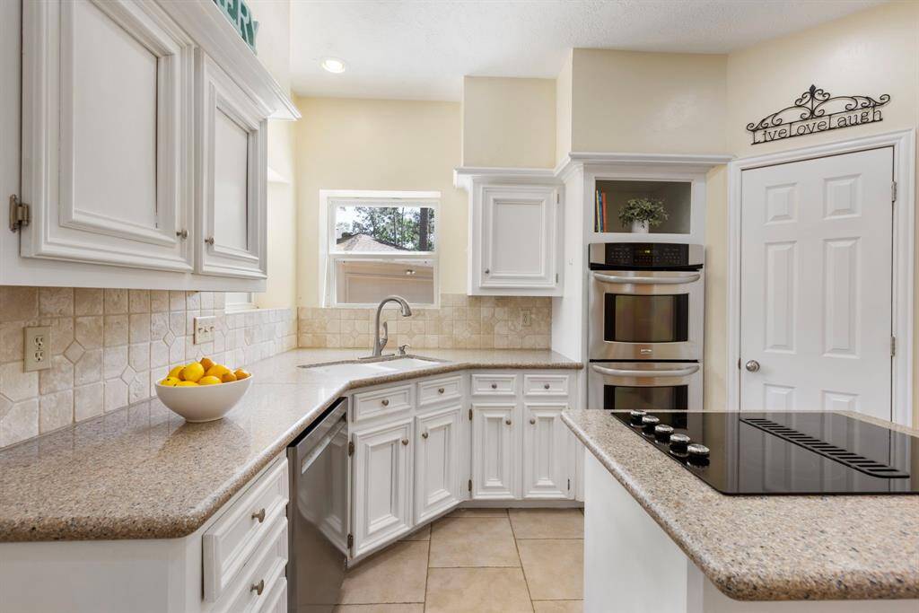 Prepare your favorite meals in this chef's dream kitchen, featuring beautiful granite countertops, double ovens, a newer dishwasher, and a sleek stove—everything you need for cooking in style.