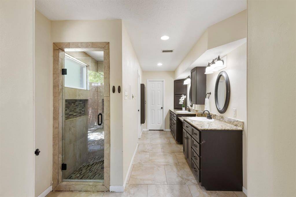 The updated primary bathroom features his and hers sinks along with plenty of cabinet storage.
