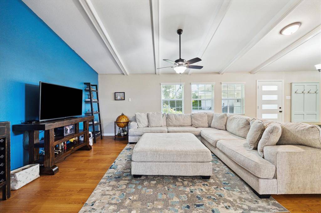 Alternate view of the living space showcasing the beamed ceiling and laminate wood flooring.