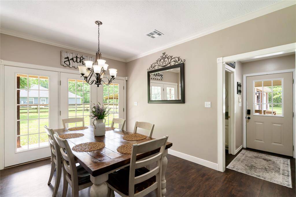 Natural light fills the dining space through large windows overlooking the backyard. Positioned near the French doors for convenient access to the patio and outdoor living areas.