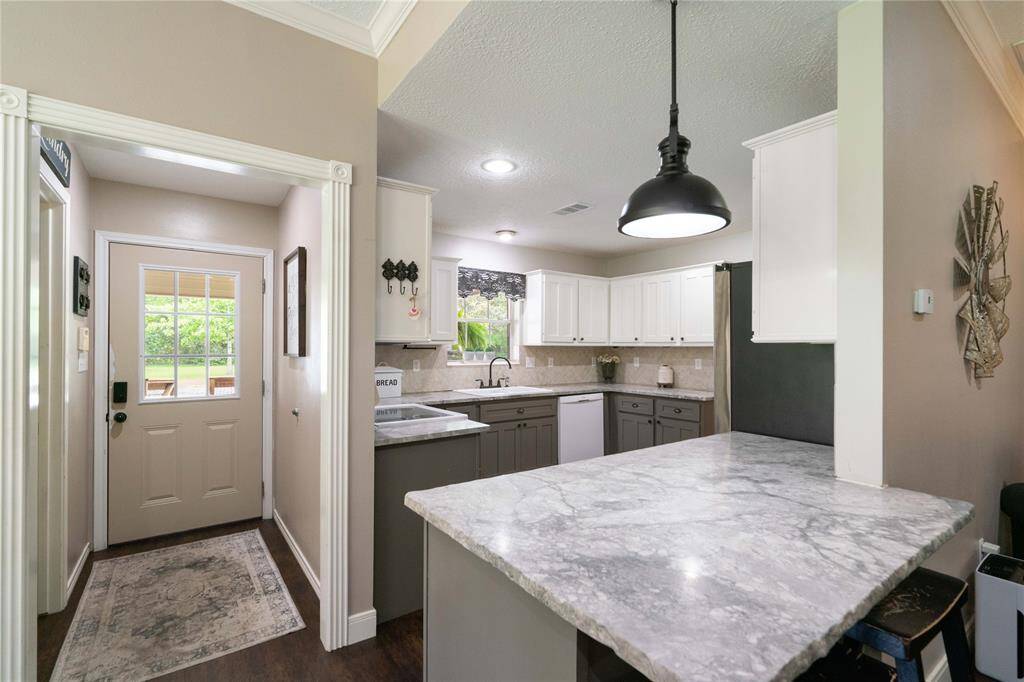 Functional kitchen entry with updated lighting, bar seating, and great visibility into the dining and living areas. Ideal setup for everyday living and hosting.