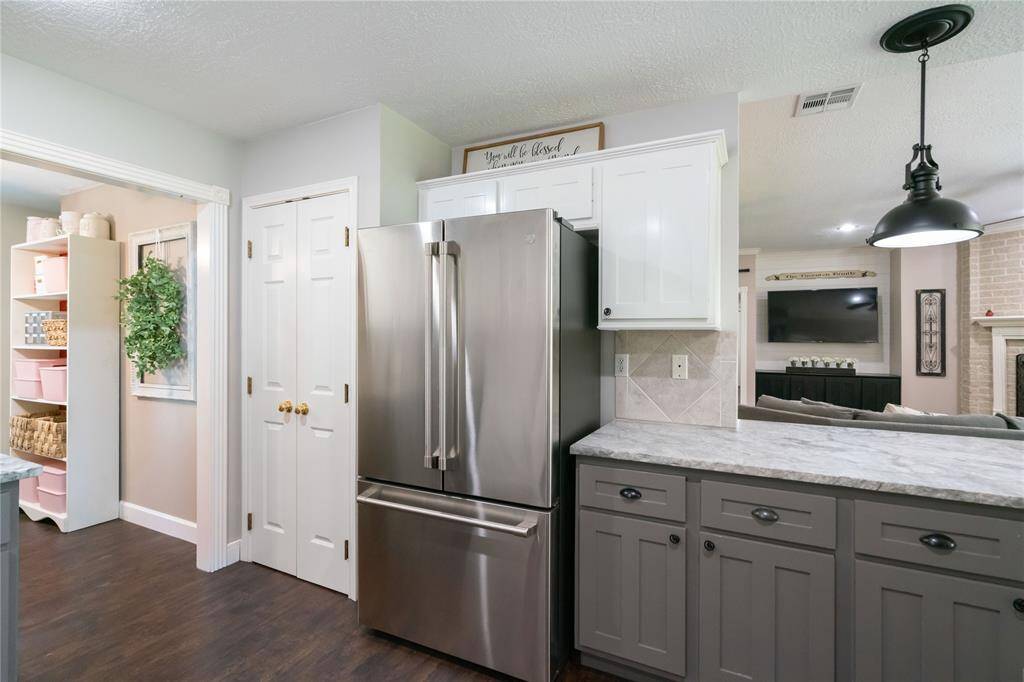 Built-in pantry and stainless steel refrigerator with nearby access to the laundry area. Efficient layout makes meal prep and storage easy.