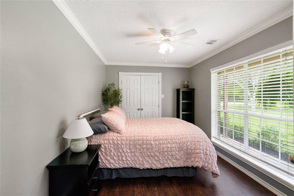 Originally designed as a den or office, this room is currently used as a fourth bedroom. Features include crown molding, wood-style flooring, and a wall of windows offering great natural light and front yard views—perfect as a guest space, study, or second living area.