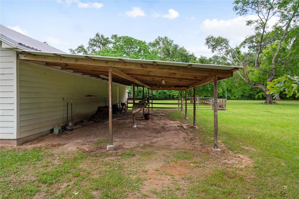 A large covered structure on the side of the 3-car garage offers flexible use for equipment storage, firewood, bikes, tools, or even a future workshop space. Positioned with easy access to the backyard and open pasture.