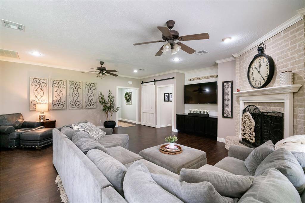 Comfortable living space featuring dual ceiling fans, a barn-style sliding door, and natural light that enhances the home’s layout.