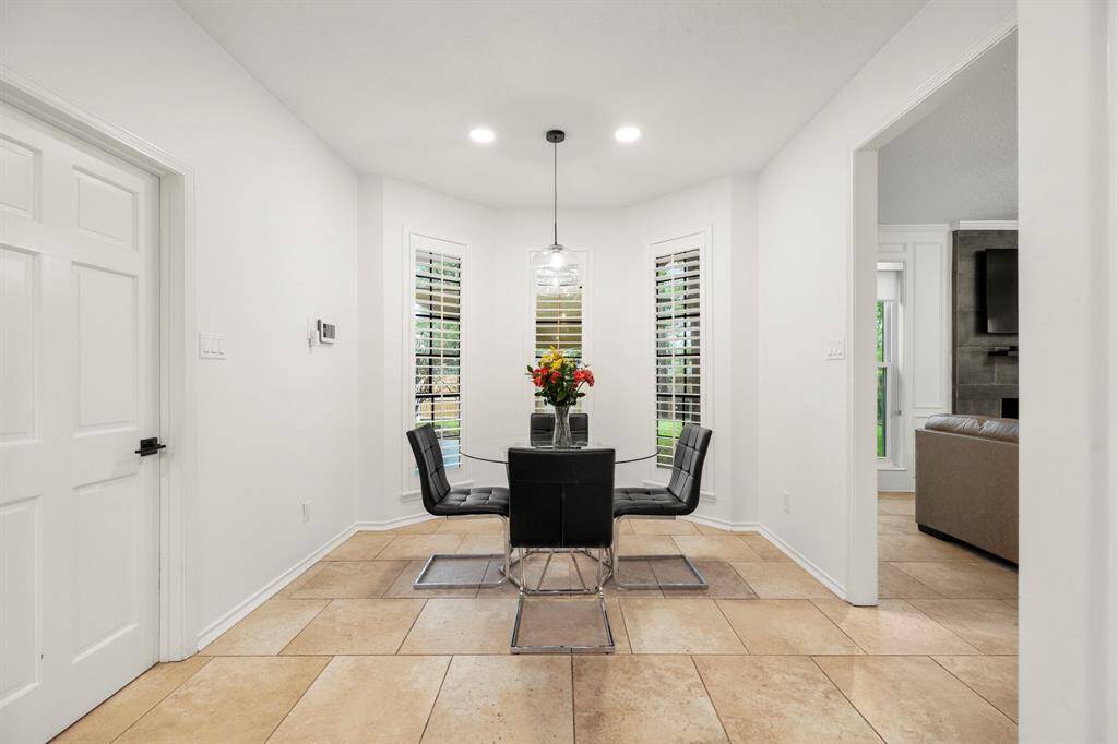 As we turn around, the kitchen is now behind us, offering a clear view of the bright breakfast area with bay windows that fill the space with natural light. To the left, the door leads to the laundry room, while the opening to the right leads into the living room. Plantation shutters adorn the windows, adding a touch of elegance to the space.