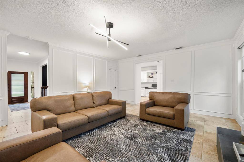 Taken from near the fireplace, this angle offers a glimpse into the kitchen on the right, highlighting the home's open layout. To the left, we can see back into the foyer and staircase, adding to the home's spacious feel. The door by the entrance to the kitchen leads to a convenient understairs closet for additional storage.