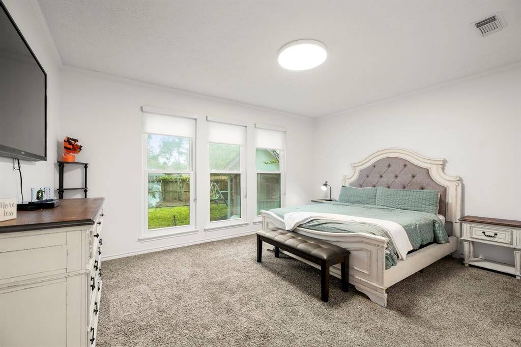 The downstairs primary bedroom offers a peaceful retreat with large windows that overlook the backyard, filling the space with natural light and offering a serene view.
