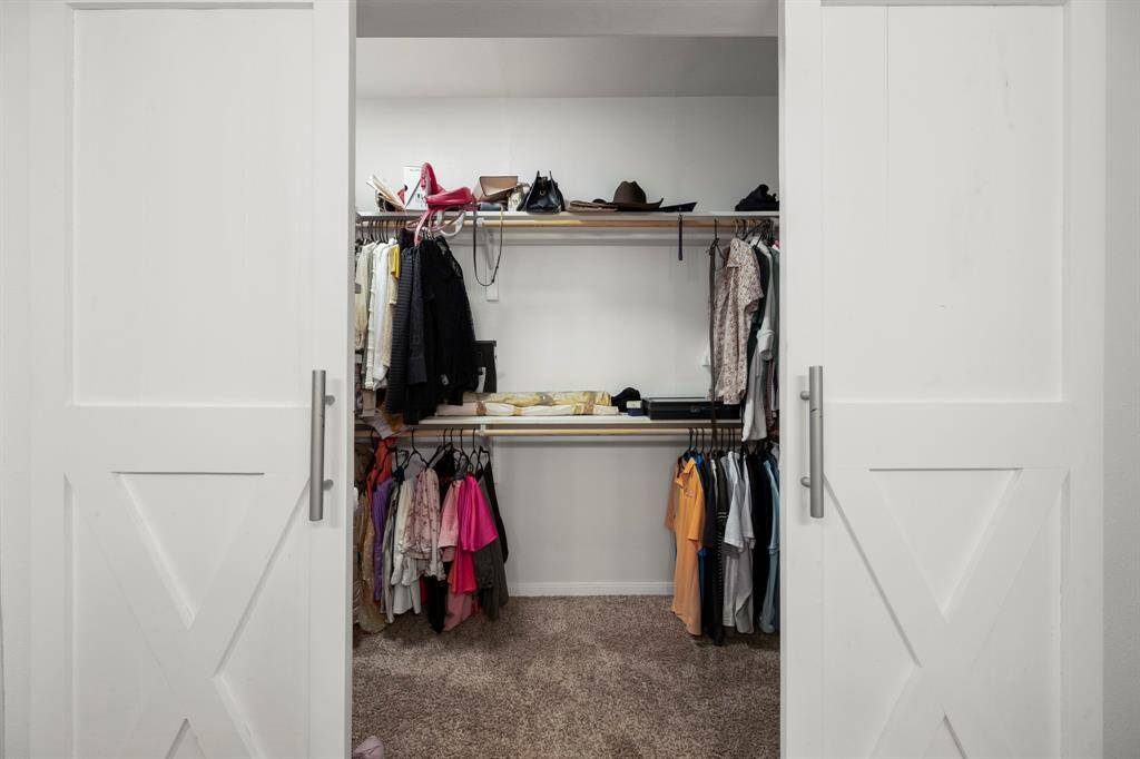 A peek behind the sliding barn doors reveals the expansive walk-in closet, extending to both the left and right, offering plenty of storage space for your wardrobe and accessories.