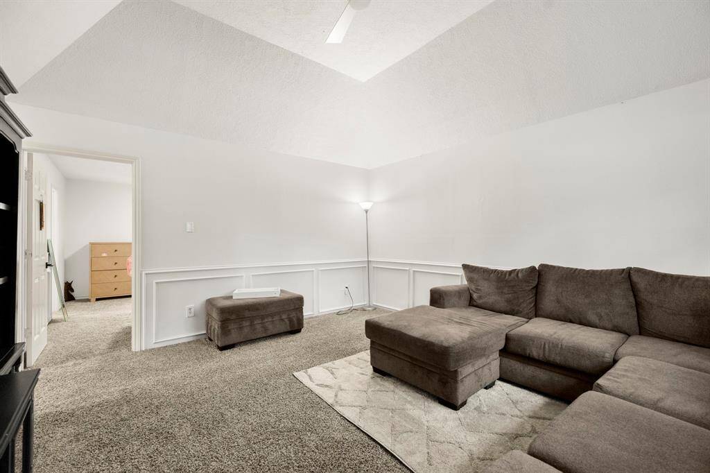 Another view of the upstairs living area/game room highlights the spaciousness of the room, with its vaulted ceilings and natural light streaming in through the large window.